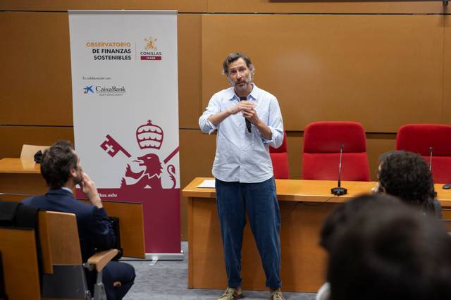 Un hombre está hablando en una sala con público, frente a un cartel del Observatorio de Finanzas Sostenibles.