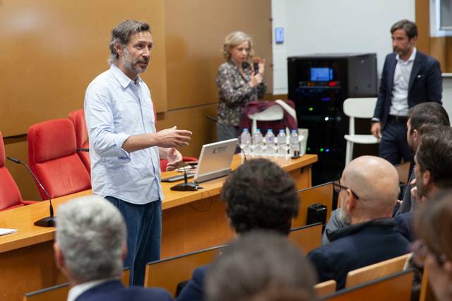 Un orador presenta en un evento, mientras el público lo escucha atentamente.