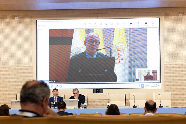 Un hombre habla en una conferencia mientras se proyecta su imagen en una pantalla grande.