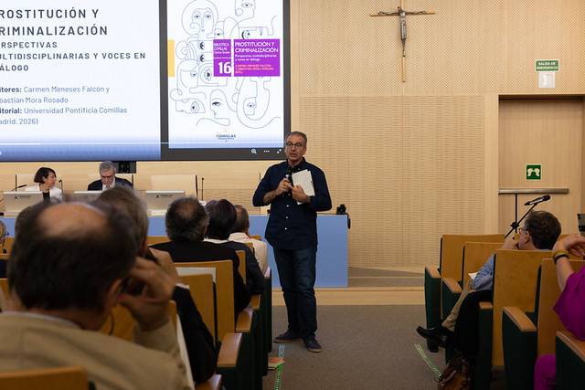 Una conferencia sobre prostitución y criminalización con un presentador hablando frente a la audiencia.