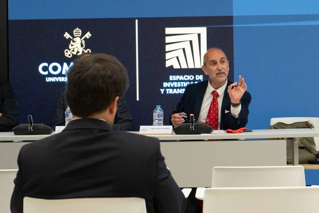 Un hombre habla ante un grupo en una mesa de conferencia.