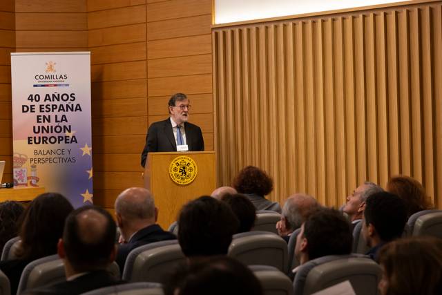 Un orador presenta un evento sobre los 40 años de España en la Unión Europea ante una audiencia sentada.