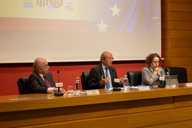 Tres personas sentadas en una mesa durante un evento o conferencia.