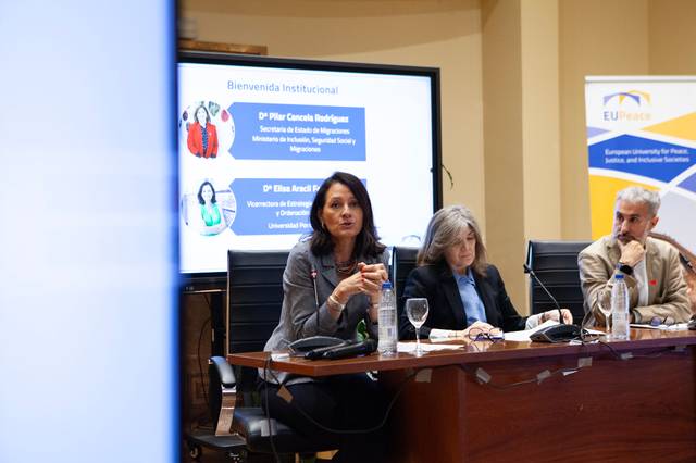 Una mesa redonda con tres personas discutiendo en un evento académico.