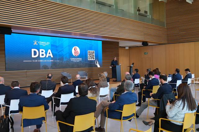 Un evento académico con un ponente frente a una audiencia en un ambiente moderno.