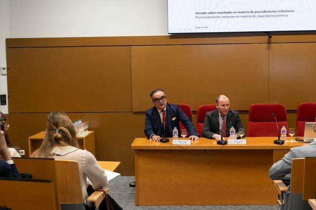 Una reunión sobre novedades en procedimientos tributarios con varios participantes en una mesa de conferencia.