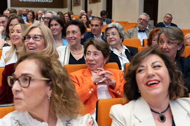 Un grupo de personas sonrientes en un evento, sentados en un auditorio.