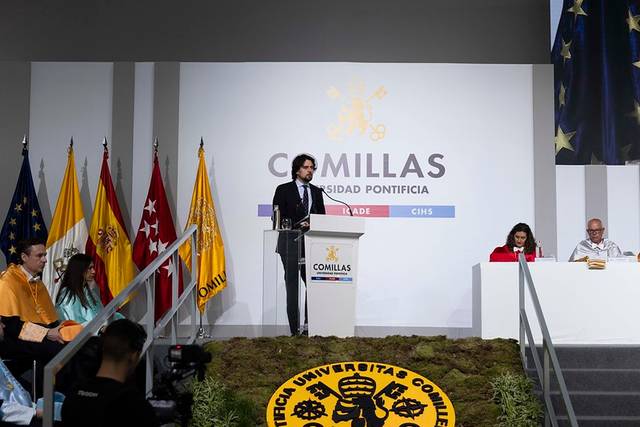 Un evento académico en la Universidad Pontificia Comillas con oradores y banderas de España.