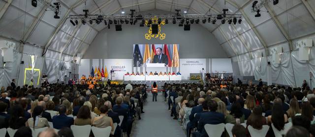 Un evento masivo en un recinto cerrado con un ponente en el escenario frente a un público numeroso.