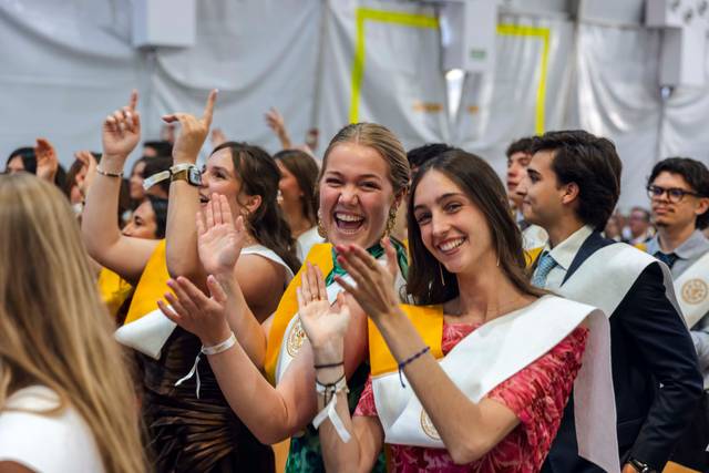 Un grupo de jóvenes celebra con entusiasmo en un evento, aplaudiendo y sonriendo.