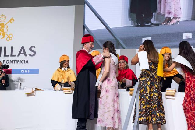 Un ceremoniante está colocando una medalla a una graduada en un evento oficial.