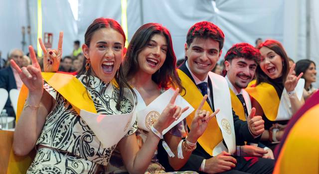 Un grupo de jóvenes celebra con sonrisas y gestos alegres durante una ceremonia de graduación.