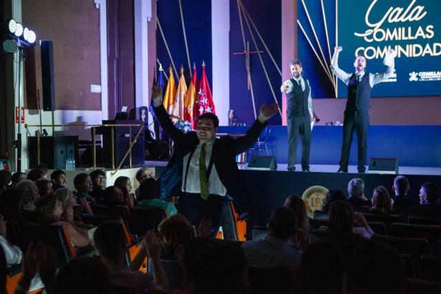 Un momento divertido en una gala donde un hombre interactúa con los presentadores en el escenario.