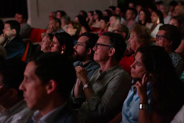 Una multitud de personas sentadas en un auditorio escuchando atentamente.