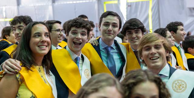 Un grupo de estudiantes sonrientes en una ceremonia de graduación, luciendo togas y birretes.