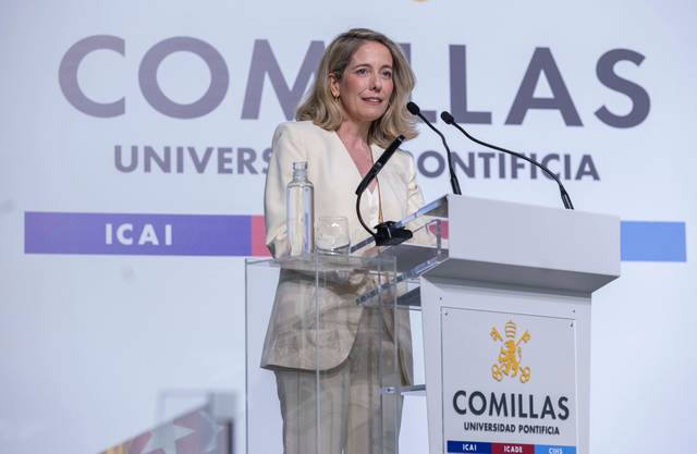 Una mujer está dando un discurso en un podio de la Universidad Pontificia Comillas.