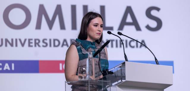 Una mujer joven habla en un podio durante un evento universitario.