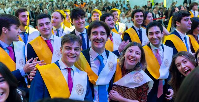 Un grupo de estudiantes celebra su graduación con sonrisas y togas en un ambiente festivo.