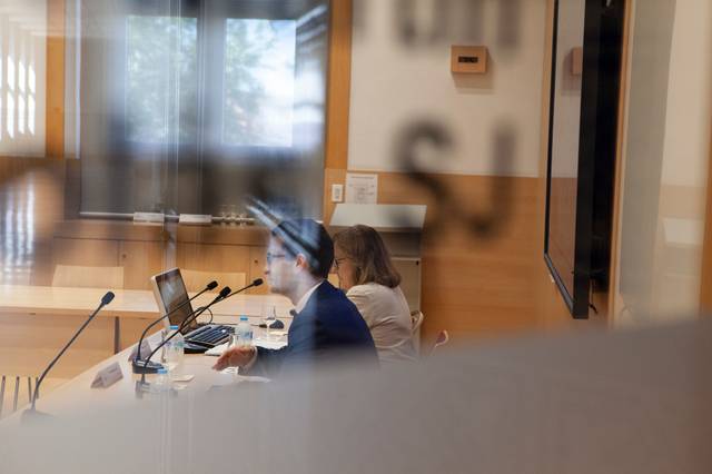 Una reunión en un salón con personas hablando y un proyector en funcionamiento.