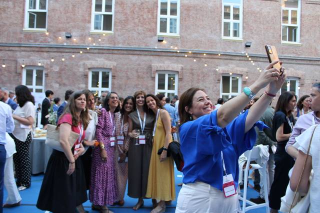 Un grupo de mujeres sonrientes se toma una selfie en un evento al aire libre.