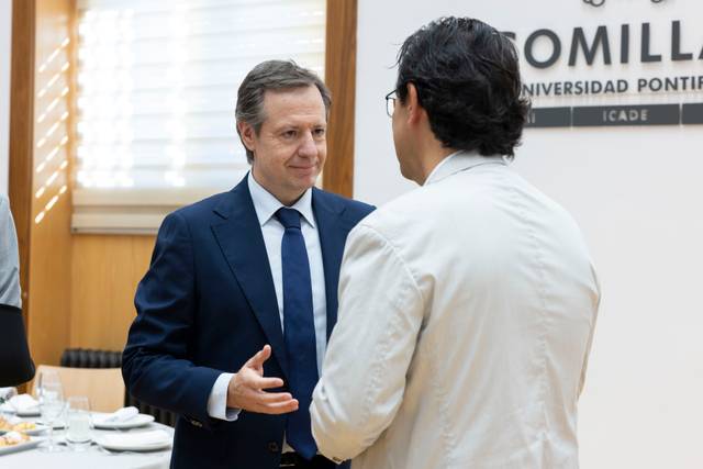 Dos hombres conversan en un entorno elegante durante un evento en la universidad.