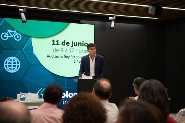 Un hombre habla desde un podio en un auditorio mientras presenta un evento programado para el 11 de junio.
