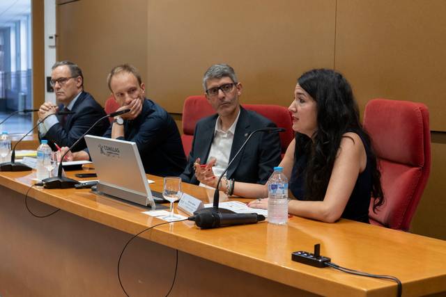 Una mesa redonda donde varios panelistas discuten un tema mientras una mujer expone su punto de vista.