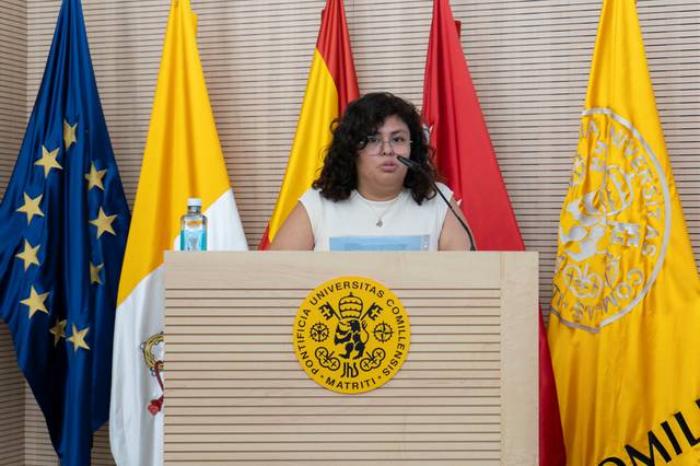 Una persona está hablando en un podio frente a varias banderas.