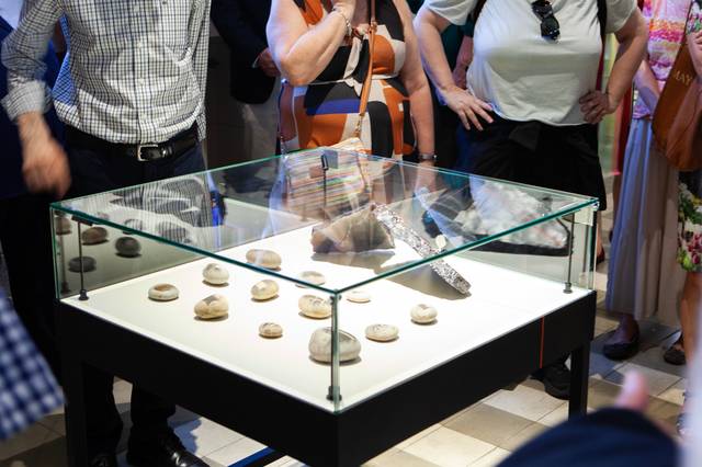 Un grupo de personas observa una vitrina con varios objetos en un museo.