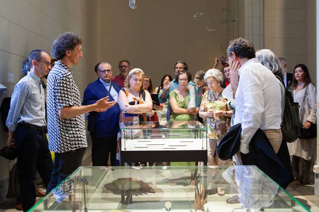 Un grupo de personas observa una exposición en un museo mientras un guía explica el contenido.