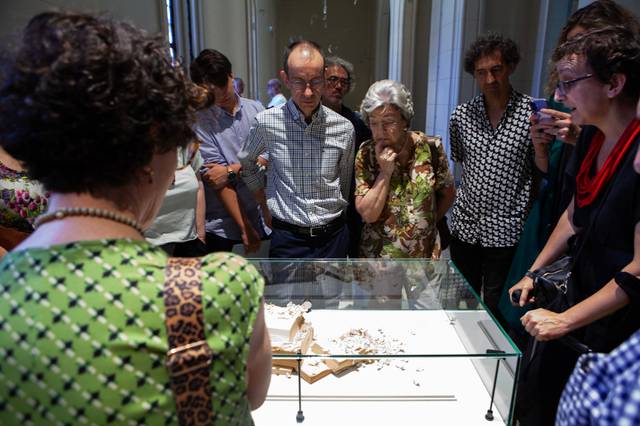 Un grupo de personas observa atentamente una vitrina en una exposición.