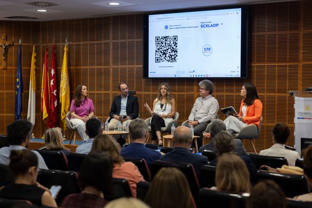 Un panel de discusión con varios ponentes frente a una audiencia en un evento.