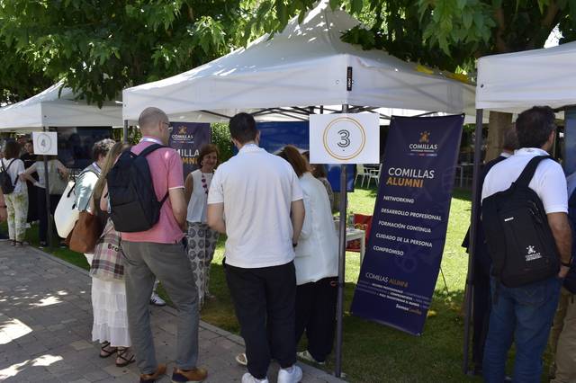 Un grupo de personas interactuando en un evento al aire libre con carpas y stands informativos.