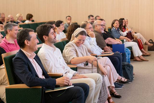 Un grupo de personas sentadas en un auditorio durante un evento.