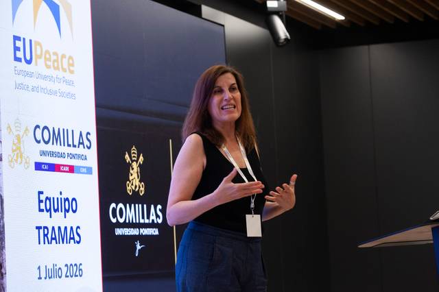 Una mujer está dando una presentación en un evento académico en la Universidad Pontificia Comillas.
