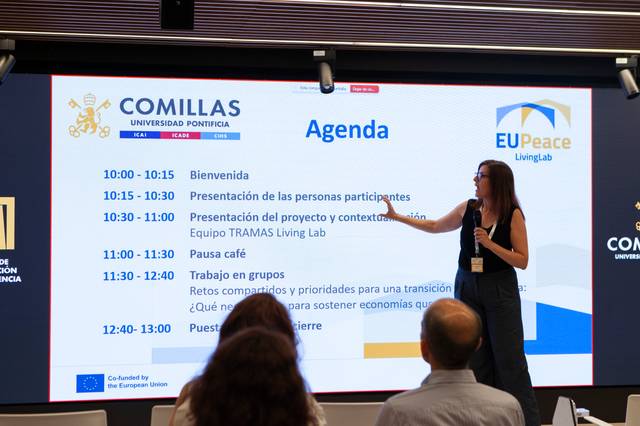 Una presentadora muestra la agenda de un evento en una pantalla grande en la Universidad Pontificia Comillas.