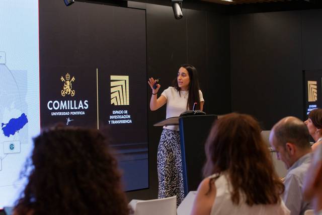 Una mujer presenta un tema en una conferencia en la Universidad Pontificia Comillas.