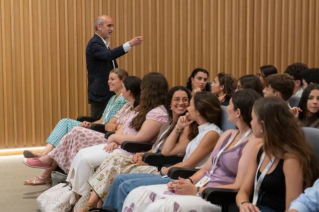 Un orador está dirigiéndose a un grupo de jóvenes en un auditorio.