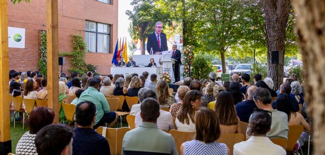 Un evento al aire libre con un orador en un escenario y un público atento.