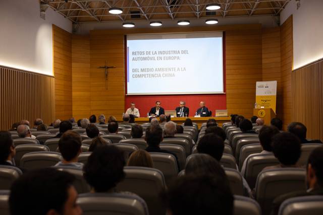 La imagen muestra a un panel de expertos discutiendo sobre los retos de la industria del automóvil en Europa frente a la competencia china en un evento público.