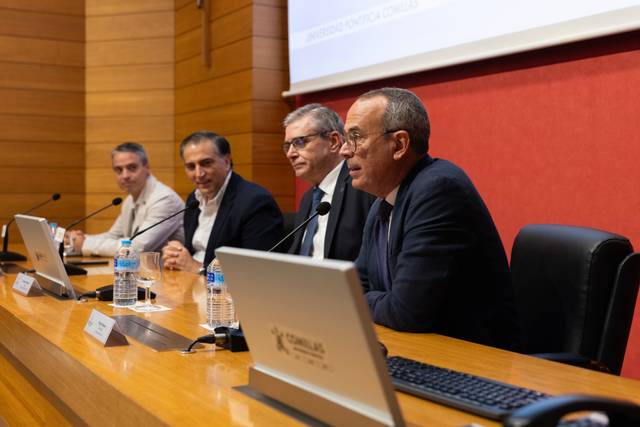 Un grupo de cuatro hombres discute en una mesa durante un evento o presentación.