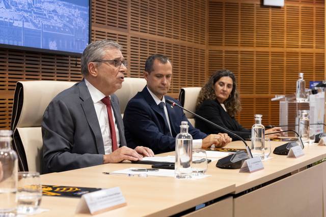 Un grupo de tres personas discute en una mesa durante una presentación.