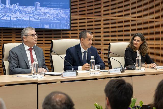 Una conferencia o rueda de prensa con tres personas sentadas en una mesa, dos hombres y una mujer, discutiendo temas importantes.