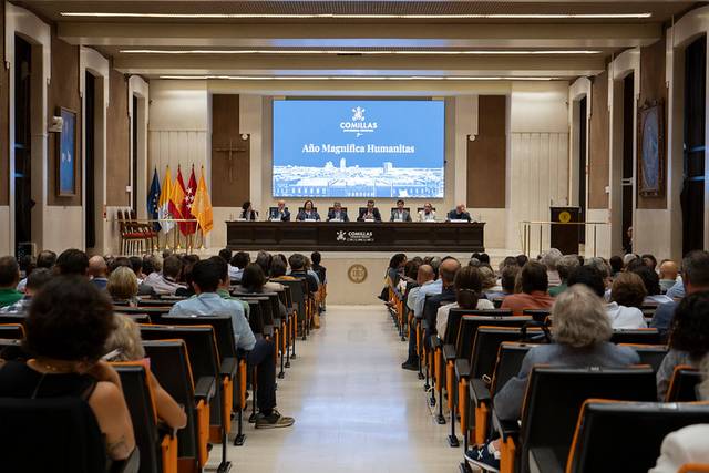 Un evento formal en un auditorio con un panel de ponentes al frente y una audiencia sentada.