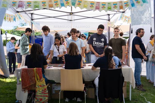 Un grupo de personas participa en un evento al aire libre, mientras se encuentran en un puesto con varias actividades y decoraciones.