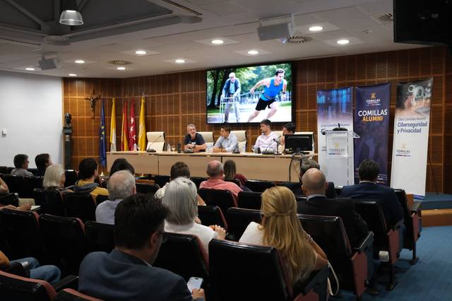 Un grupo de personas asiste a una conferencia en un auditorio con una presentación proyectada en la pantalla.