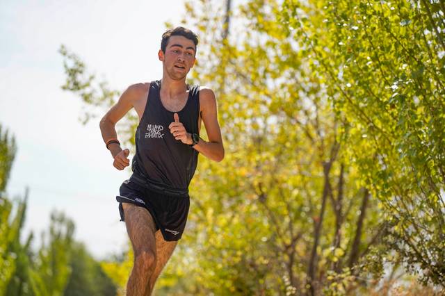 Un joven corre por un camino rodeado de árboles y vegetación.