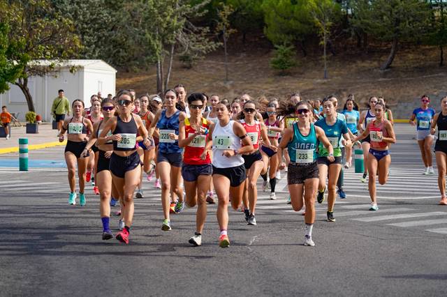 Un grupo de mujeres corre en una competición atlética al aire libre.