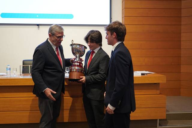 Un grupo de tres personas en un evento de premiación sosteniendo un trofeo.