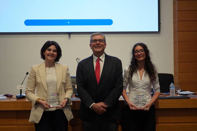 Una ceremonia de premiación con dos galardonadas y un hombre en el medio.